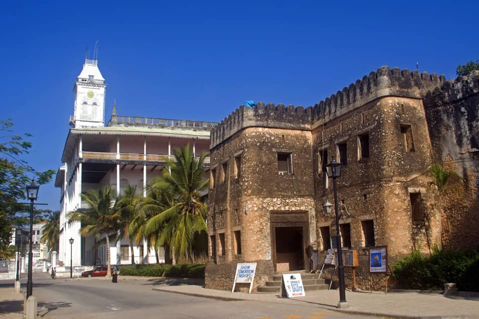 Historic Stone Town fort with white clock tower under a clear blue sky